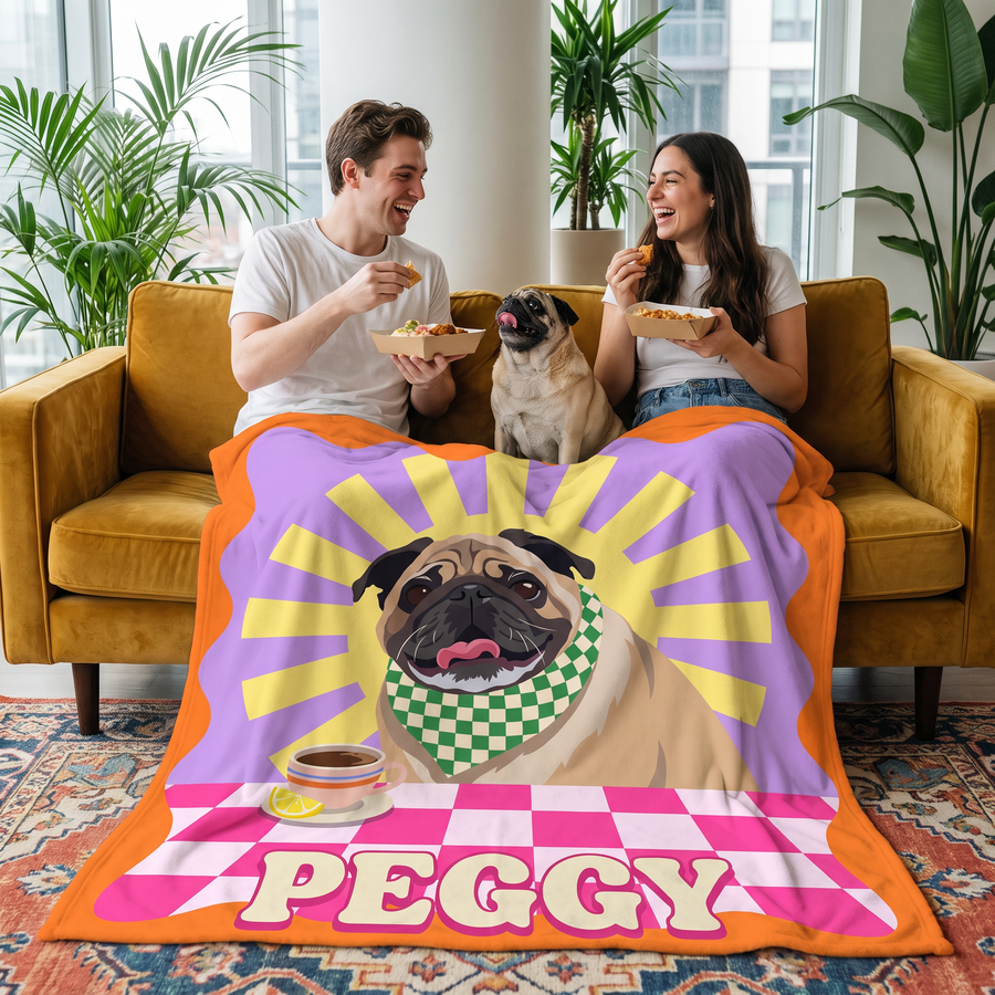 Couple sharing a takeaway on a mustard sofa under a Fancy Pups pug blanket