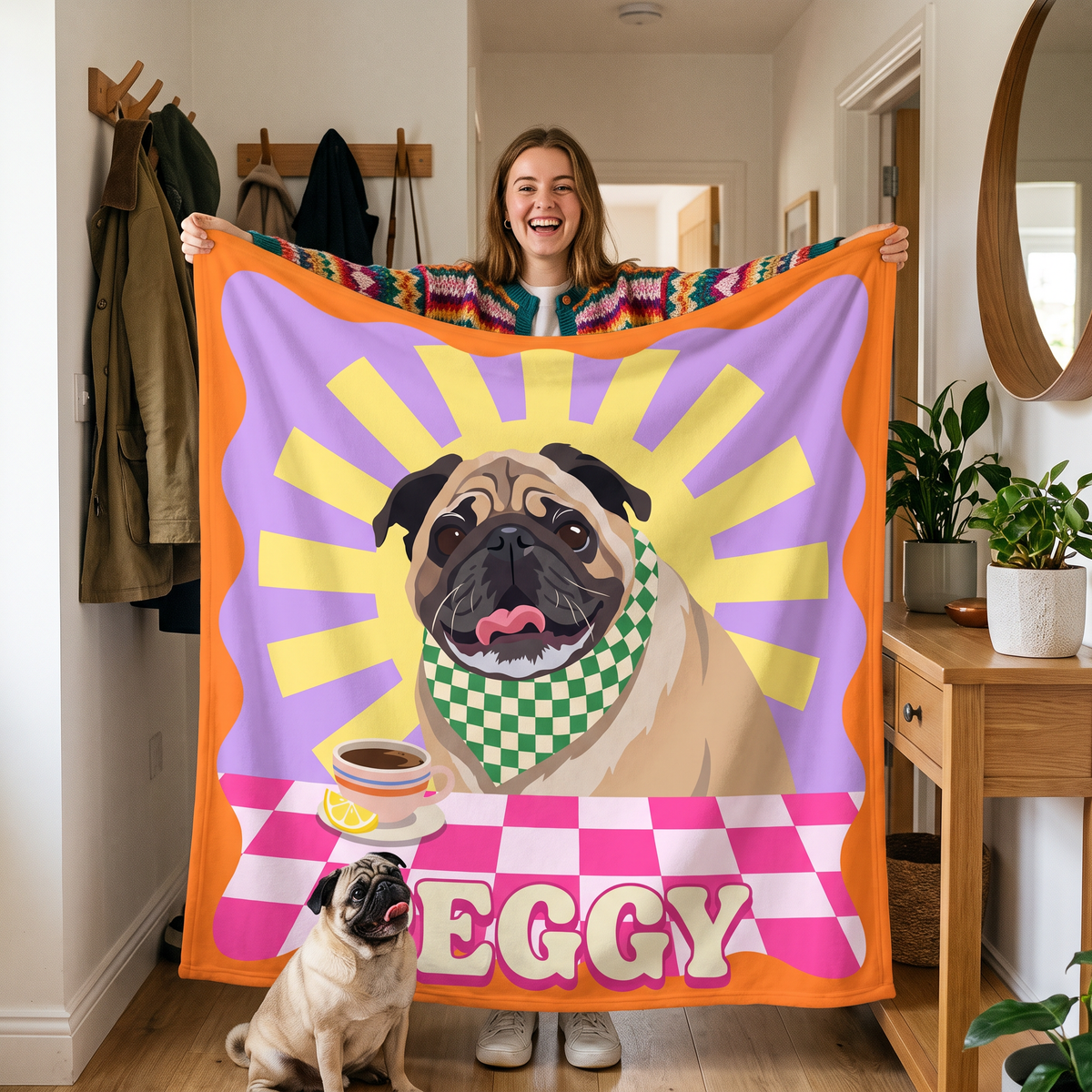 Woman holding up her personalised pop art pug blanket with her pug at her feet