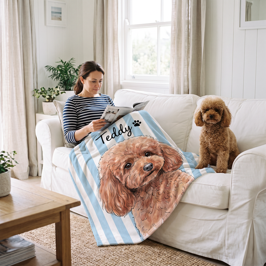 Woman reading on a white sofa under a striped poodle portrait blanket with her dog