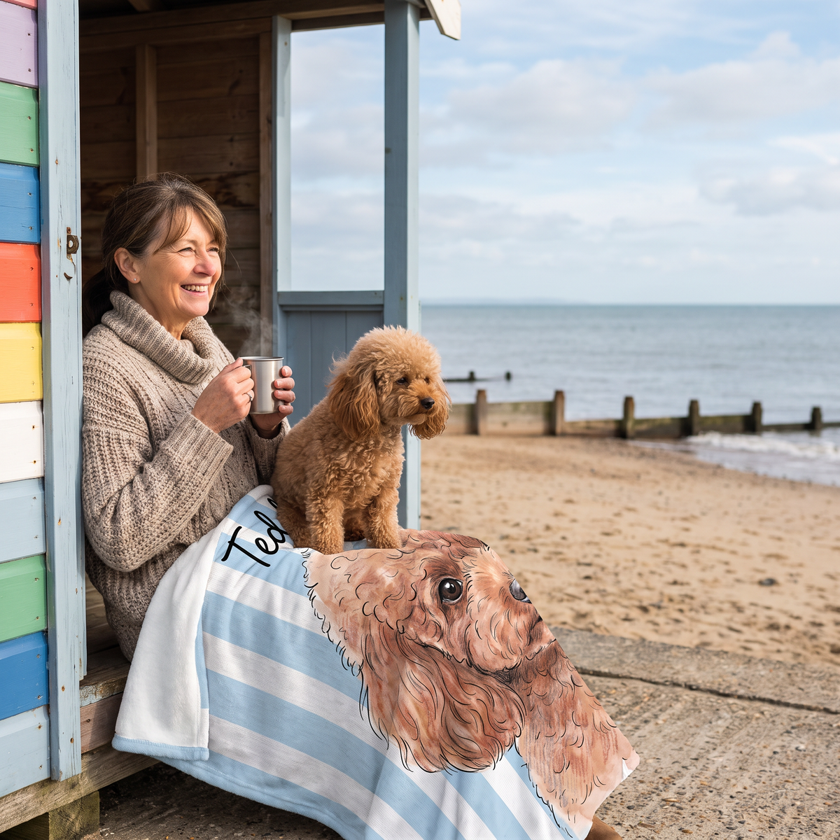 Woman in a beach hut doorway wrapped in a striped pet portrait blanket with her poodle